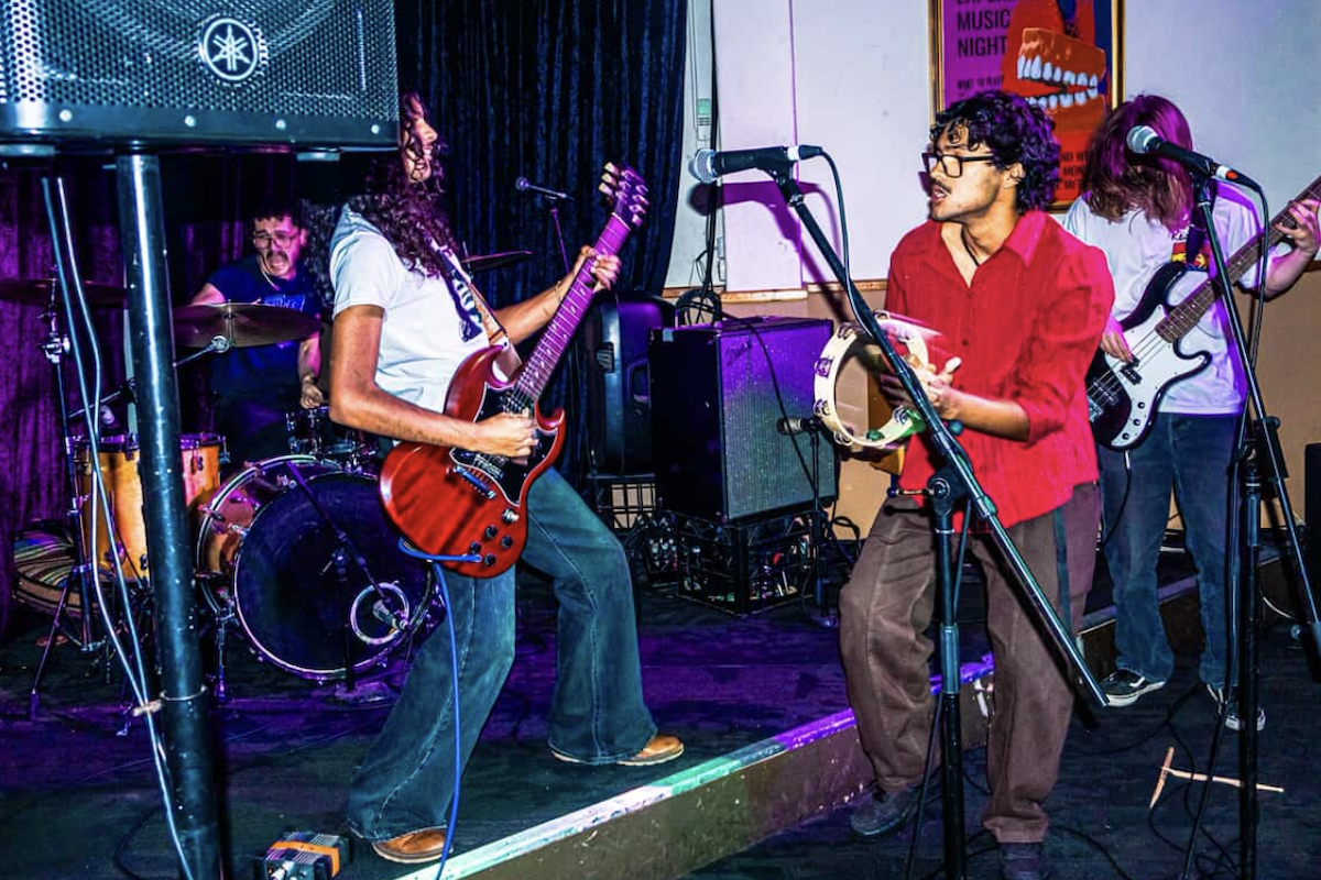 Adelaide band Jaded Earth performing live on stage with electric guitars, vocals, tambourine, and drums at a venue.